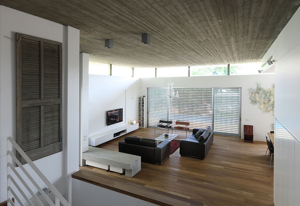 Photo of a medium sized modern open plan living room in Tel Aviv with white walls, dark hardwood flooring, a ribbon fireplace, a plastered fireplace surround and a wall mounted tv.
