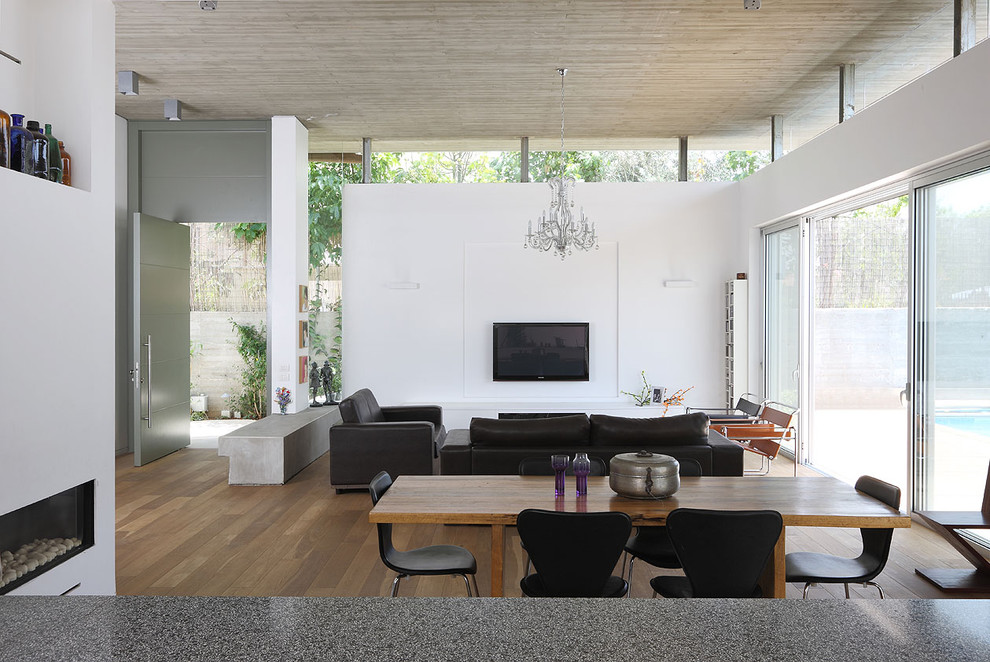 This is an example of a medium sized modern open plan living room in Tel Aviv with white walls, dark hardwood flooring, a ribbon fireplace, a plastered fireplace surround and a wall mounted tv.