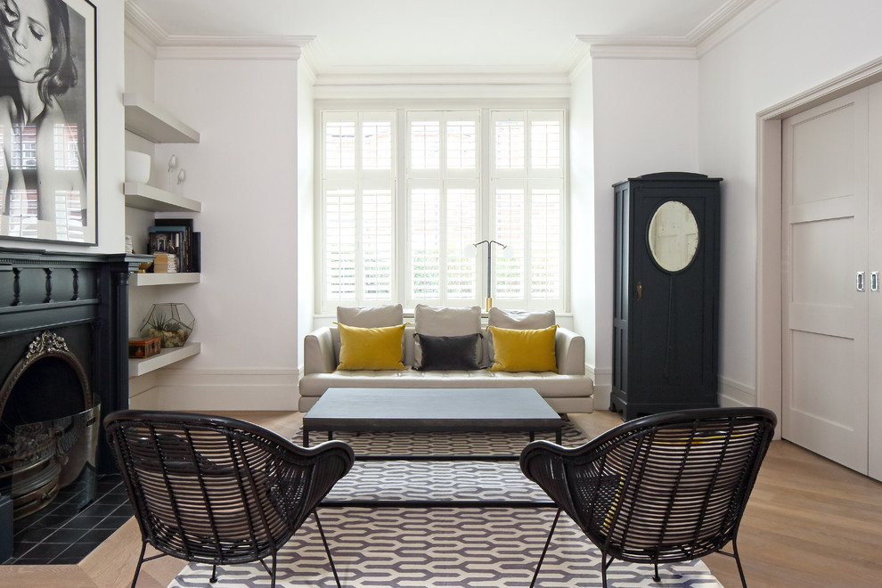 Immagine di un soggiorno classico chiuso con pareti bianche, pavimento in legno massello medio, camino classico e pavimento marrone