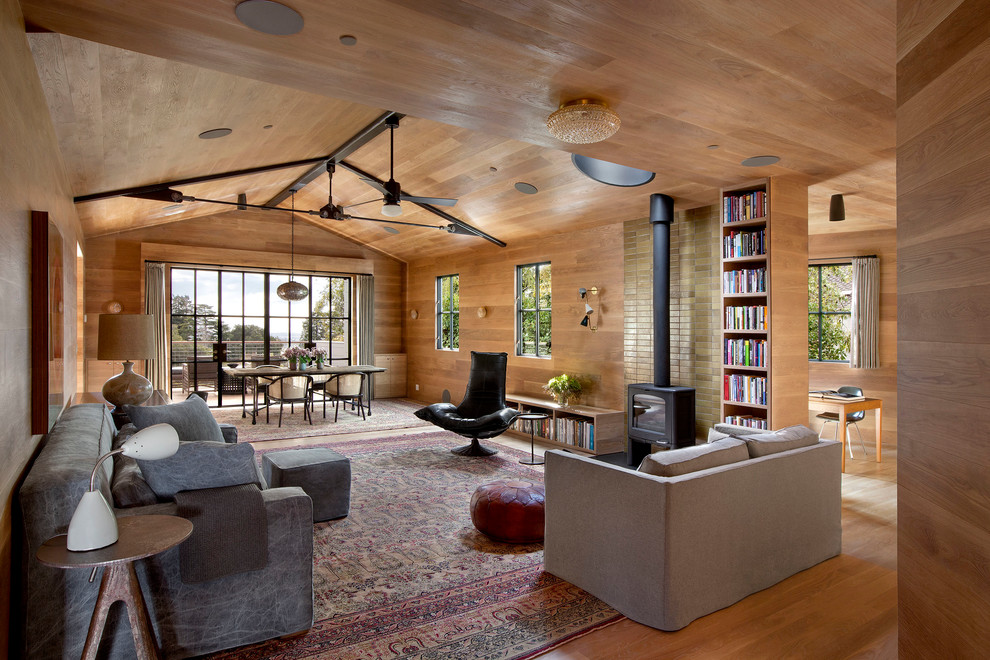 Photo of a contemporary open plan living room in San Francisco with light hardwood flooring and a wood burning stove.