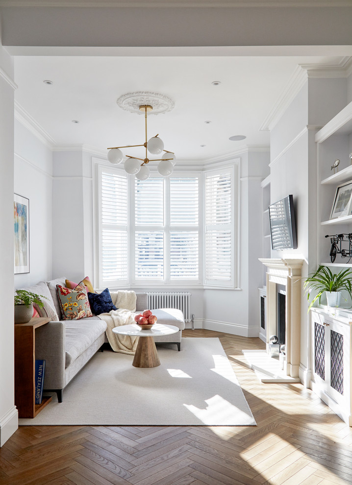 Abgetrenntes Klassisches Wohnzimmer mit bunten Wänden, braunem Holzboden, Kamin, TV-Wand und braunem Boden in London