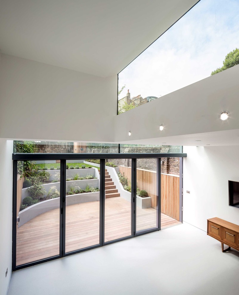 Mittelgroßes, Offenes Modernes Wohnzimmer mit weißer Wandfarbe, Betonboden, TV-Wand und grauem Boden in London