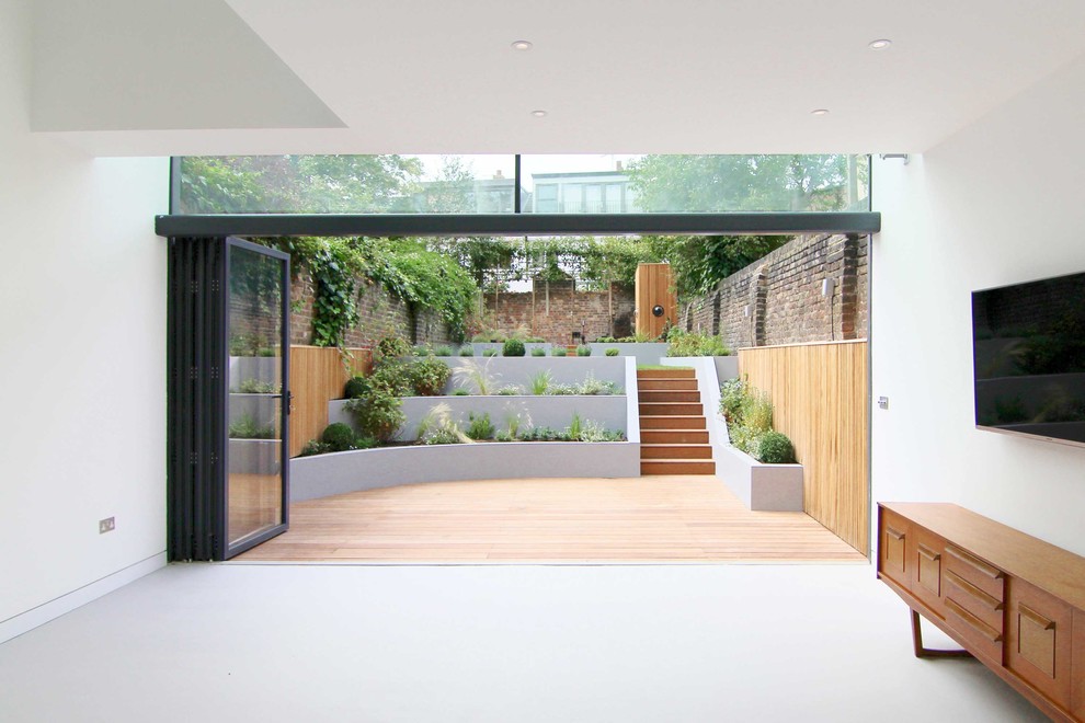Mittelgroßes, Offenes Modernes Wohnzimmer mit weißer Wandfarbe, Betonboden, TV-Wand und grauem Boden in London
