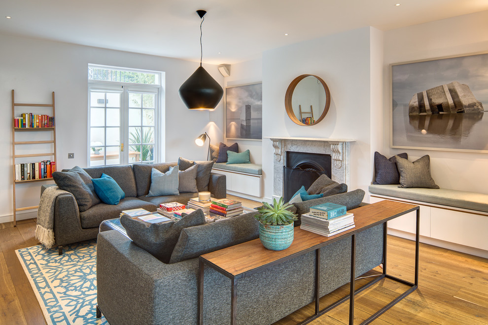 Inspiration for a transitional medium tone wood floor living room remodel in London with white walls and a standard fireplace