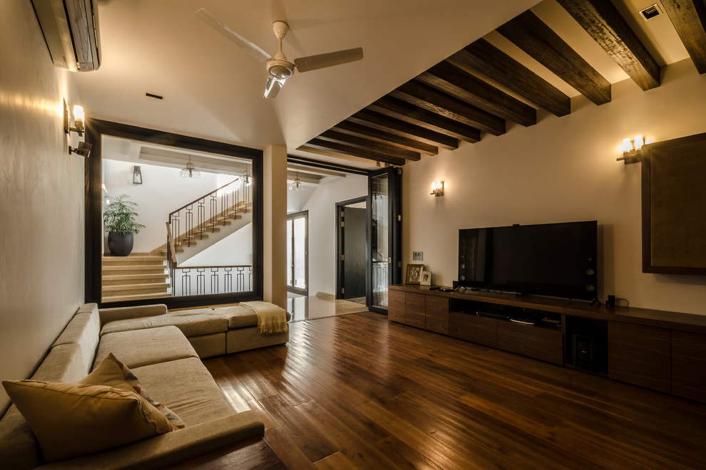 Abgetrenntes Asiatisches Wohnzimmer mit weißer Wandfarbe, braunem Holzboden, freistehendem TV und braunem Boden in Delhi