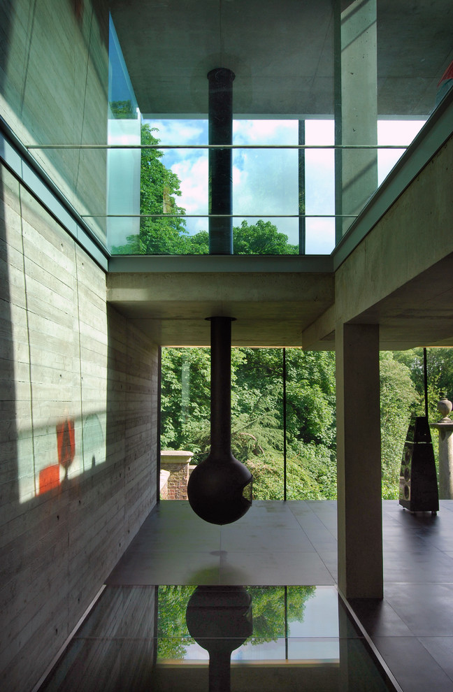 Modern inredning av ett stort allrum med öppen planlösning, med ett musikrum, grå väggar och en hängande öppen spis