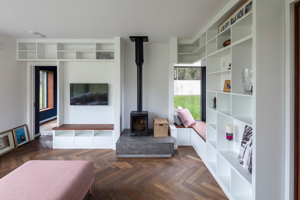 Exempel på ett stort modernt separat vardagsrum, med vita väggar, mellanmörkt trägolv, en öppen vedspis, en spiselkrans i betong, en väggmonterad TV och grått golv