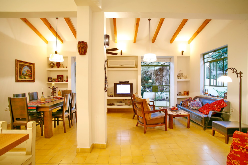 Offenes Stilmix Wohnzimmer mit freistehendem TV und gelbem Boden in Tel Aviv
