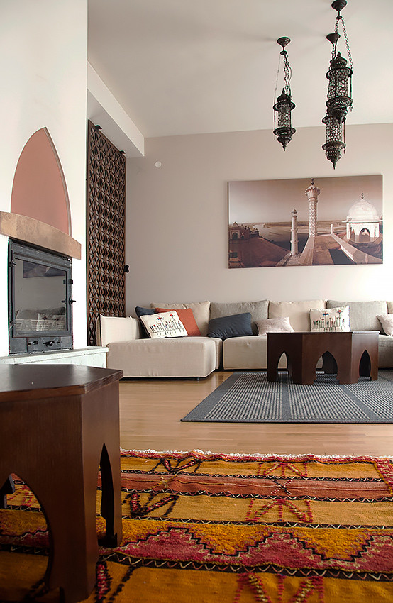 Immagine di un grande soggiorno etnico aperto con sala formale, pareti beige, parquet chiaro, camino classico e cornice del camino in intonaco