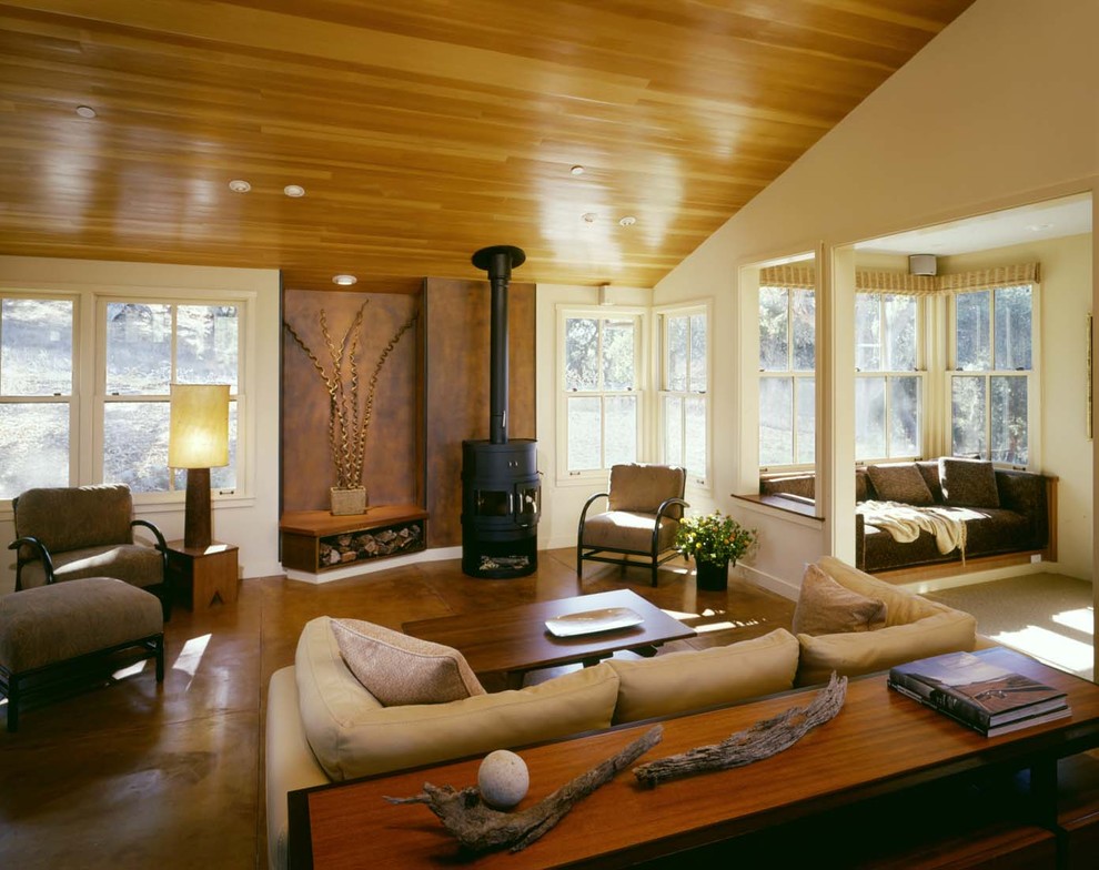 Idées déco pour un salon contemporain avec sol en béton ciré, un poêle à bois et un plafond cathédrale.