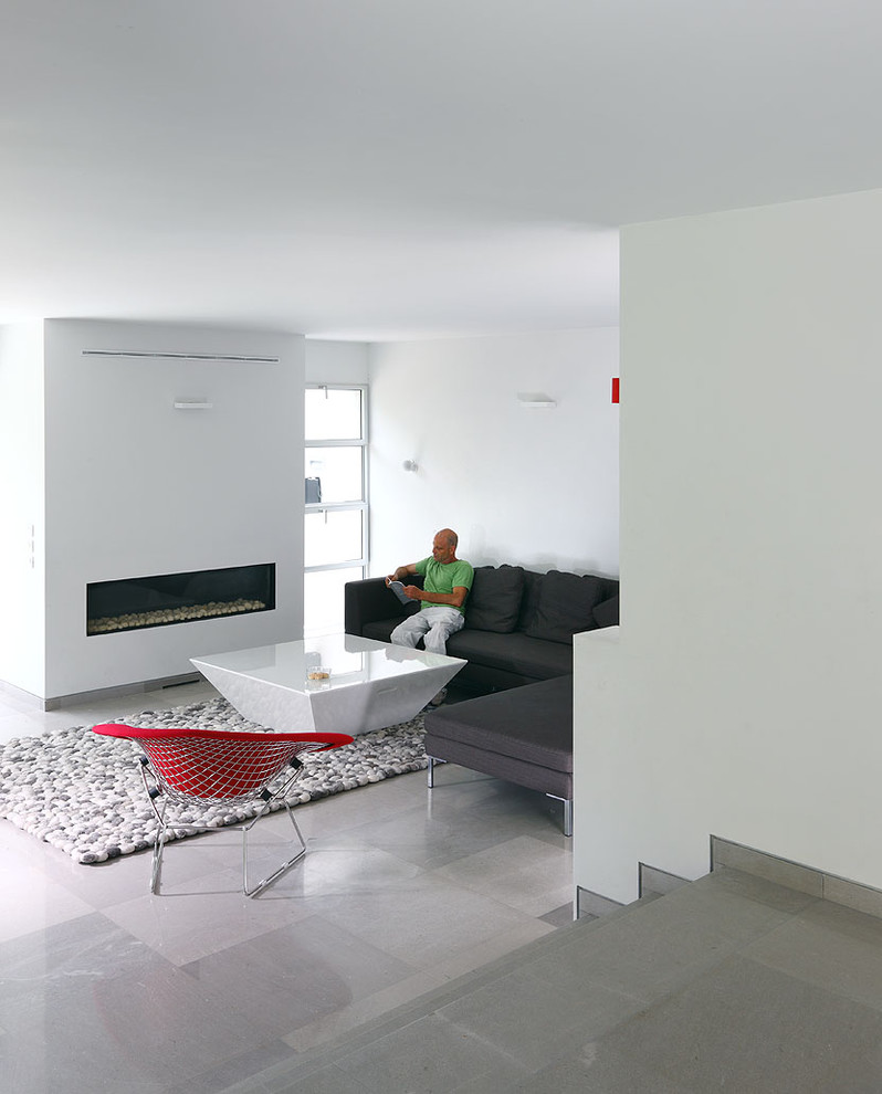 Modelo de salón para visitas cerrado moderno de tamaño medio con paredes blancas, suelo de piedra caliza, chimenea lineal, marco de chimenea de yeso y televisor colgado en la pared