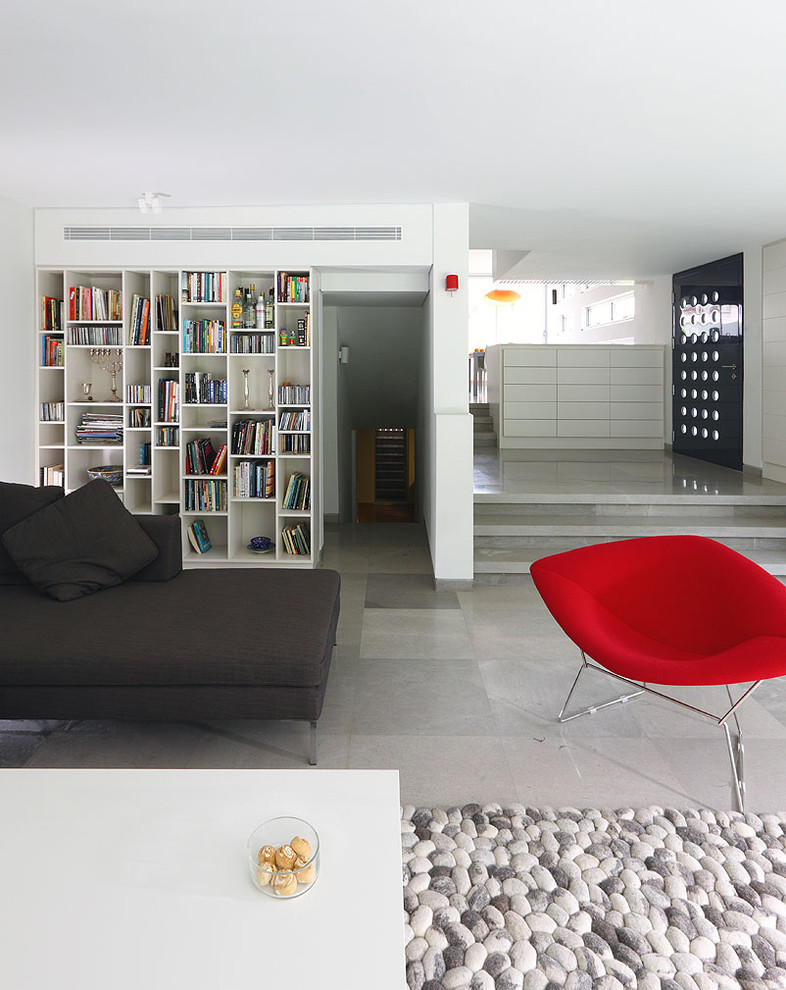 Imagen de biblioteca en casa cerrada minimalista de tamaño medio con paredes blancas, suelo de piedra caliza, chimenea lineal, marco de chimenea de yeso y televisor colgado en la pared