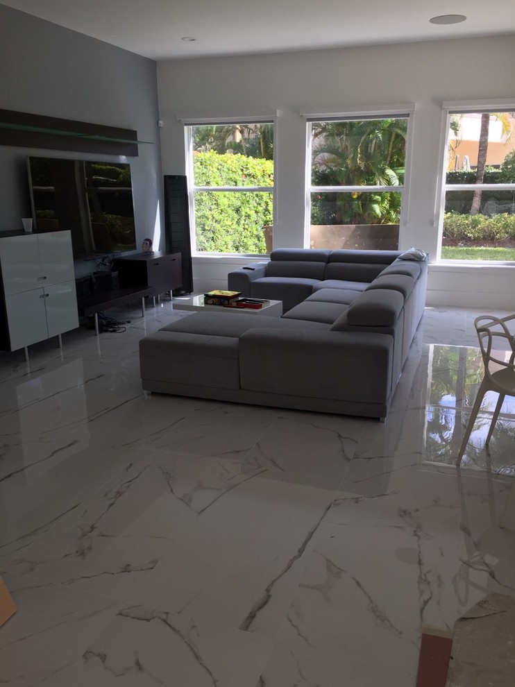 This is an example of a large modern open plan living room in Miami with porcelain flooring, grey walls, no fireplace, a wall mounted tv and white floors.