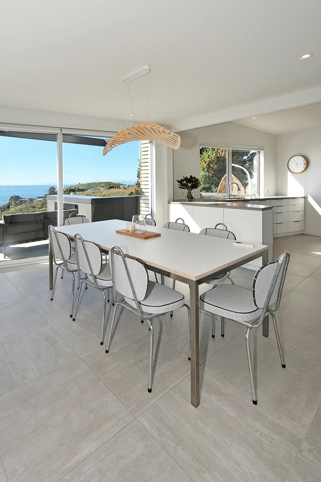 Large coastal dining room in Other with white walls, a two-sided fireplace and grey floors.
