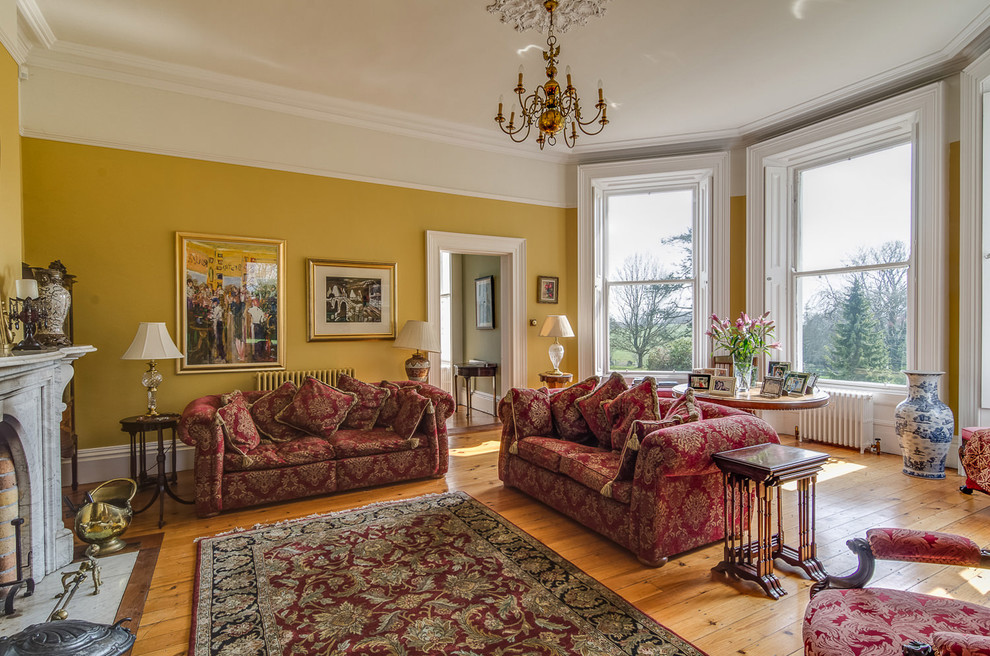 На фото: большая парадная, изолированная гостиная комната в классическом стиле с желтыми стенами, светлым паркетным полом и эркером без телевизора с