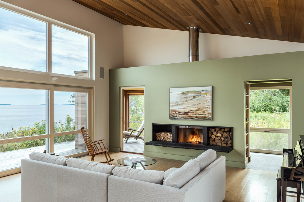 Example of a mountain style open concept light wood floor living room design in Other with green walls and a wood stove