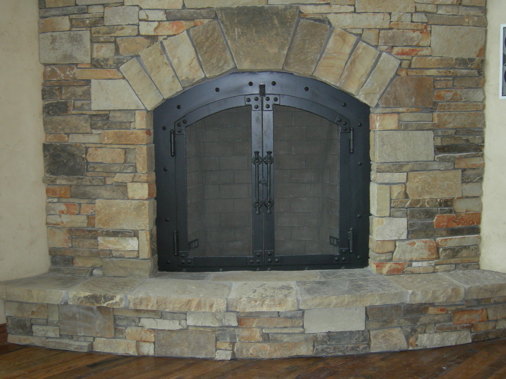 Foto de salón para visitas abierto rústico grande con estufa de leña y marco de chimenea de piedra