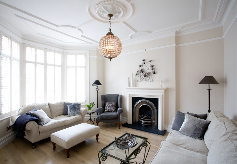 Mittelgroßes, Abgetrenntes Klassisches Wohnzimmer mit beiger Wandfarbe, hellem Holzboden, Kamin, verputzter Kaminumrandung und verstecktem TV in Surrey