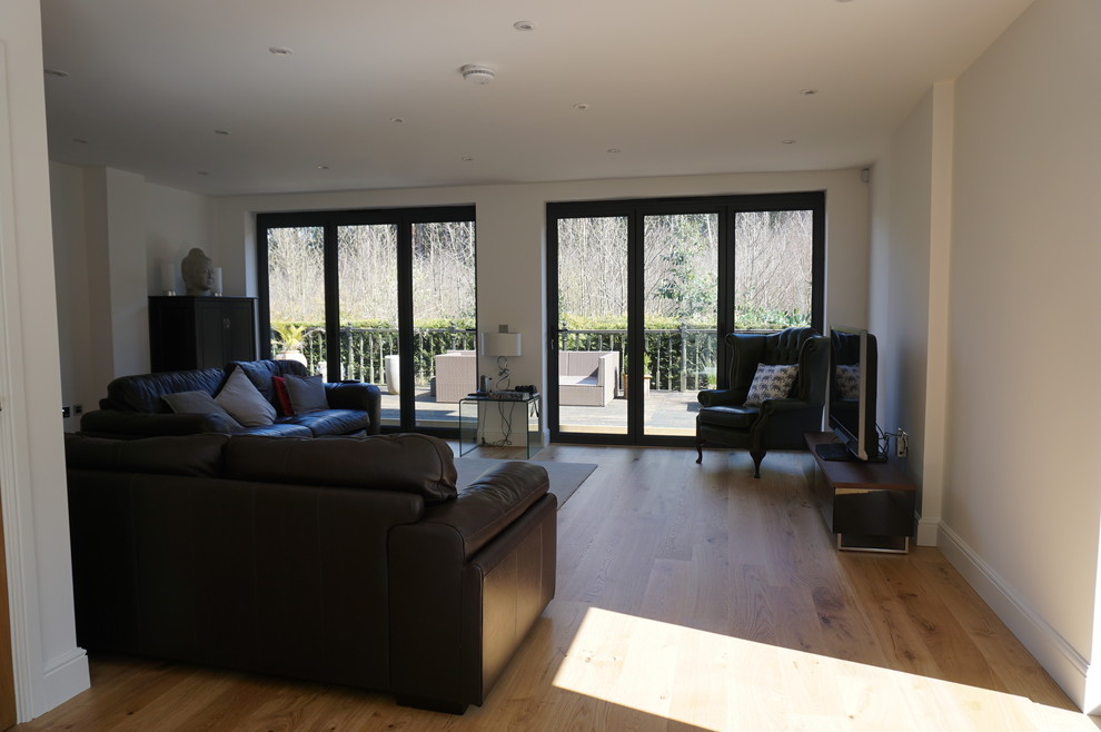 Immagine di un soggiorno moderno di medie dimensioni e aperto con pareti beige, parquet chiaro, nessun camino e TV autoportante