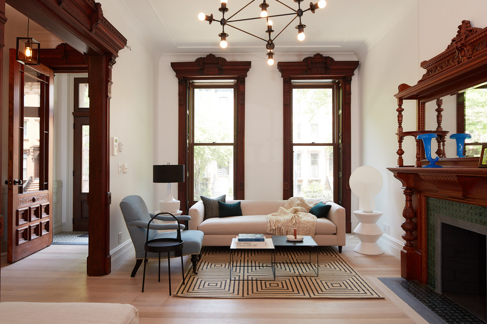 Traditional living room in New York with white walls, light hardwood flooring, a standard fireplace and beige floors.