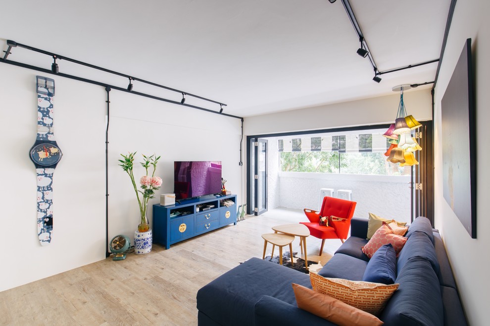 Stilmix Wohnzimmer mit weißer Wandfarbe, hellem Holzboden, freistehendem TV und braunem Boden in Singapur