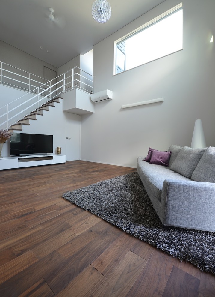 Свежая идея для дизайна: открытая гостиная комната в стиле модернизм с серыми стенами, темным паркетным полом и отдельно стоящим телевизором - отличное фото интерьера