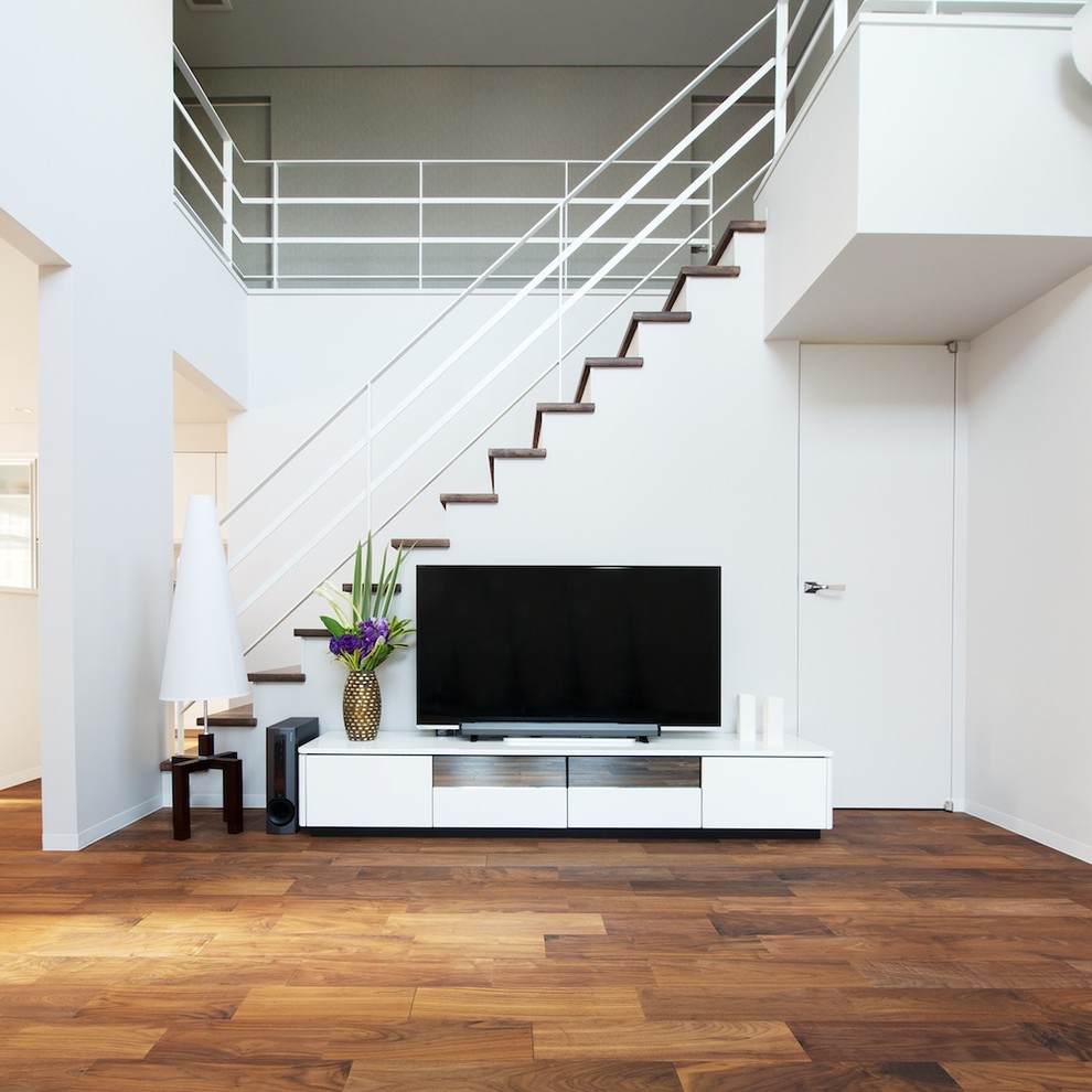 Cette photo montre un salon moderne avec un téléviseur indépendant, un mur gris, parquet foncé et un sol marron.