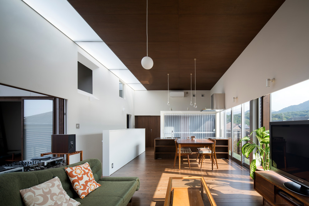 Exempel på ett modernt allrum med öppen planlösning, med vita väggar, en fristående TV, mellanmörkt trägolv och brunt golv