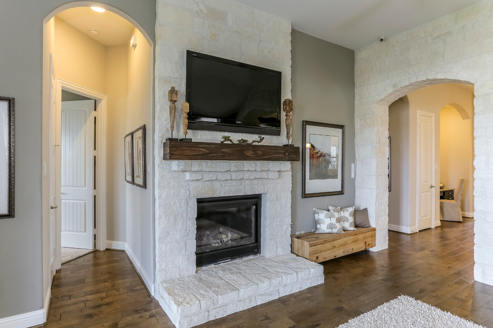 This is an example of a large classic open plan living room in Houston with beige walls, medium hardwood flooring, a standard fireplace, a stone fireplace surround and a wall mounted tv.