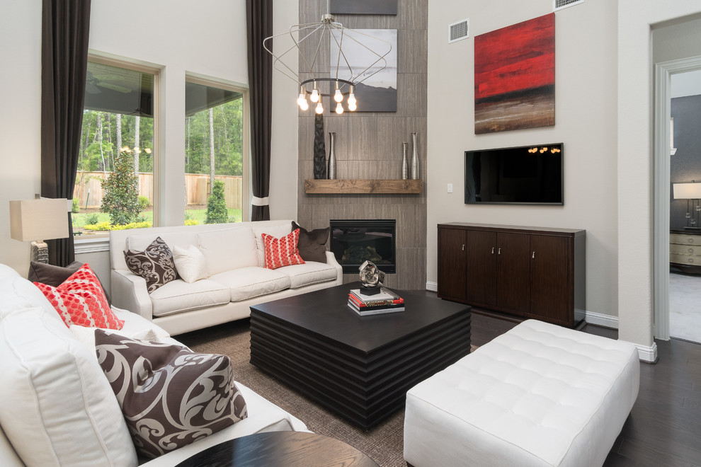 Mittelgroßes, Offenes Modernes Wohnzimmer mit beiger Wandfarbe, dunklem Holzboden, Eckkamin, gefliester Kaminumrandung, TV-Wand und braunem Boden in Houston