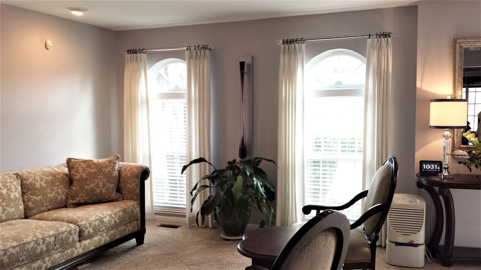 На фото: парадная, открытая гостиная комната среднего размера в стиле неоклассика (современная классика) с серыми стенами, ковровым покрытием, угловым камином и фасадом камина из дерева с