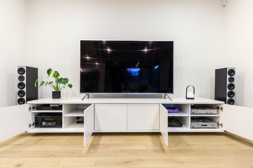 Imagen de salón abierto contemporáneo de tamaño medio sin chimenea con paredes blancas, suelo de madera clara y televisor independiente
