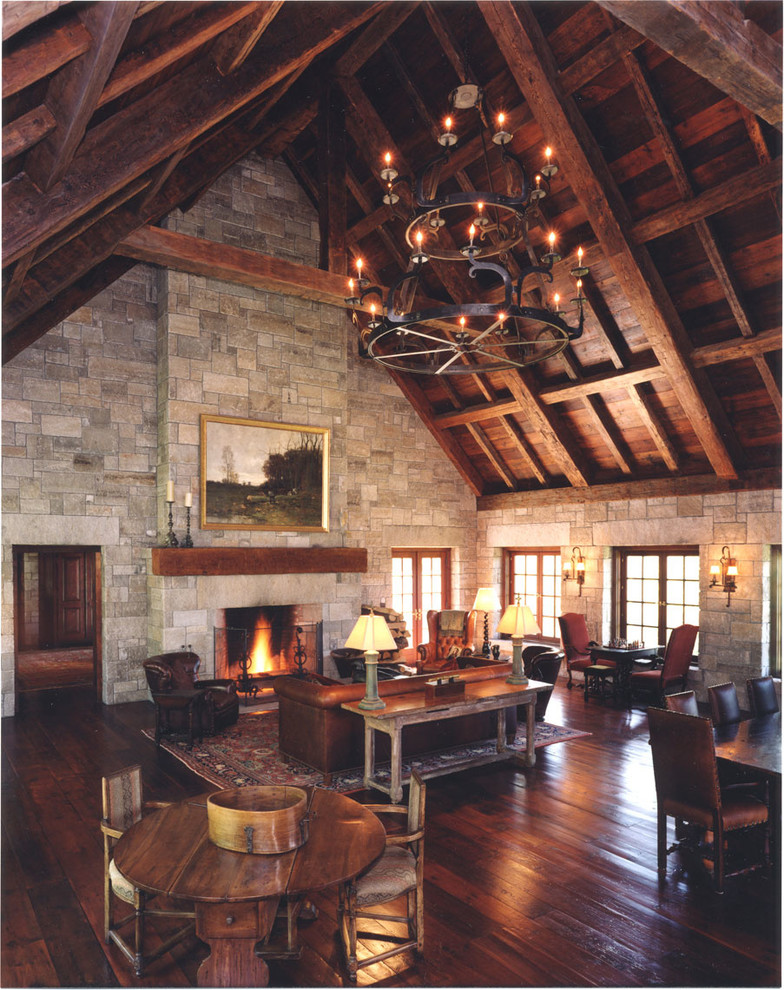 Imagen de salón para visitas abierto rural grande con paredes grises, suelo de madera oscura, todas las chimeneas y marco de chimenea de piedra