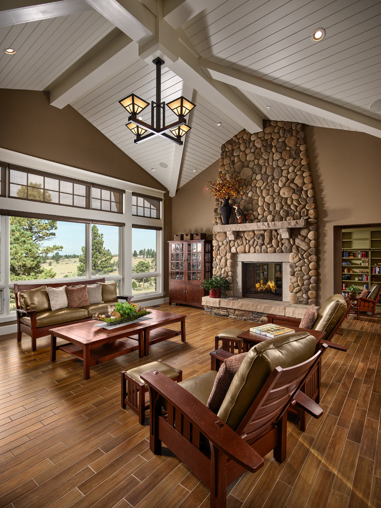 Cette photo montre un salon craftsman avec une salle de réception, un mur marron, une cheminée standard, un manteau de cheminée en pierre et un sol marron.