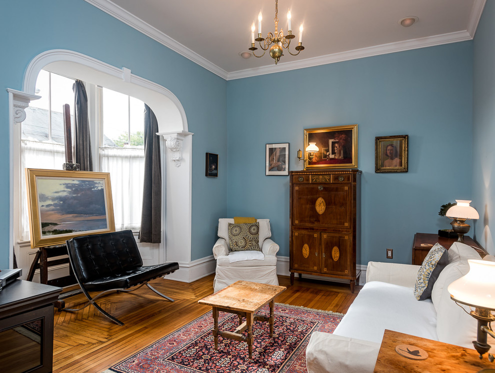 Inredning av ett modernt mellanstort separat vardagsrum, med blå väggar, ljust trägolv och en fristående TV