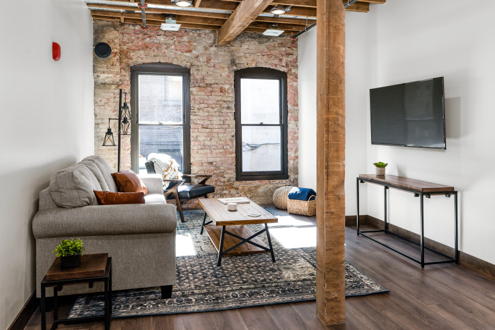 Living room - mid-sized industrial open concept light wood floor, brown floor, wood ceiling and brick wall living room idea in Other with no fireplace, a wall-mounted tv and white walls