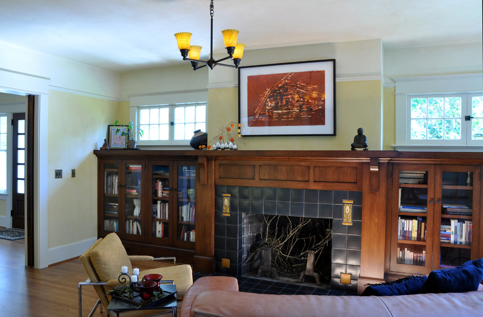 Foto de biblioteca en casa abierta de estilo americano de tamaño medio con paredes amarillas, suelo de madera en tonos medios, todas las chimeneas y marco de chimenea de baldosas y/o azulejos