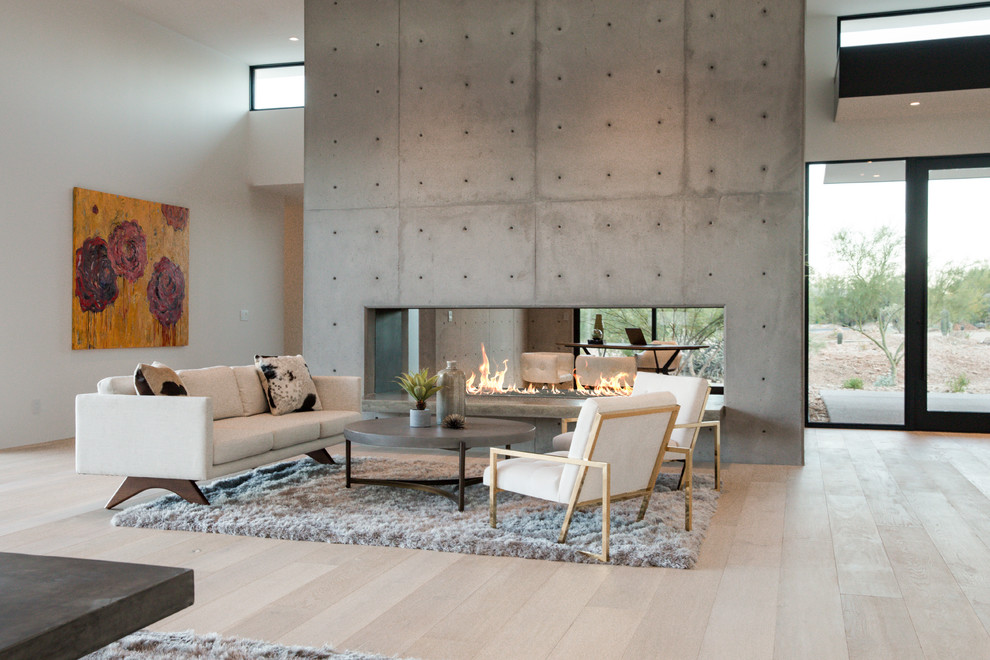 На фото: большая открытая гостиная комната в стиле модернизм с белыми стенами, светлым паркетным полом, двусторонним камином и фасадом камина из бетона с