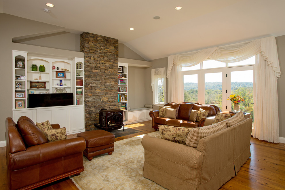 Стильный дизайн: открытая гостиная комната в классическом стиле с бежевыми стенами, светлым паркетным полом, печью-буржуйкой, фасадом камина из камня, скрытым телевизором и коричневым полом - последний тренд