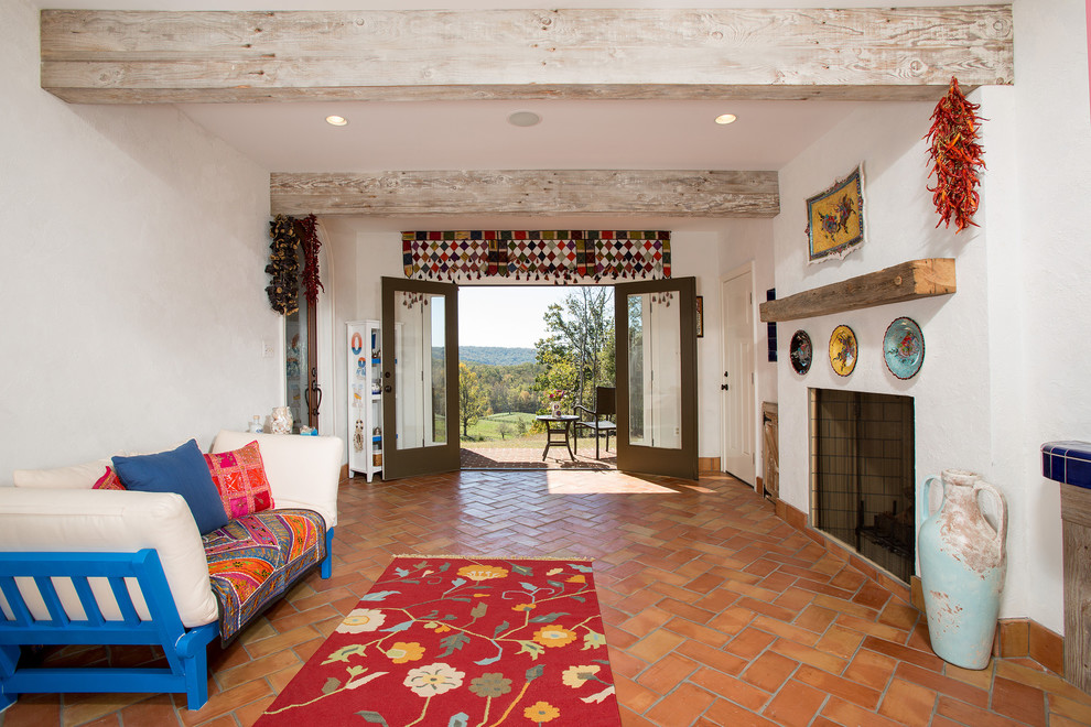 Стильный дизайн: гостиная комната в стиле фьюжн с полом из терракотовой плитки, оранжевым полом и стандартным камином - последний тренд
