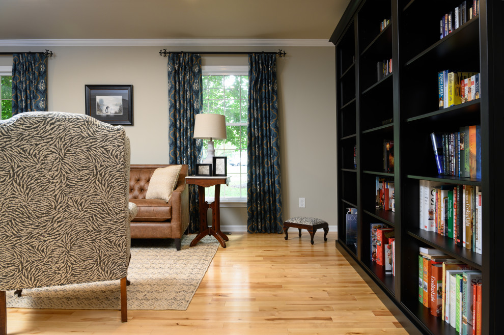 Imagen de biblioteca en casa cerrada clásica de tamaño medio con paredes beige, suelo de madera en tonos medios y suelo beige