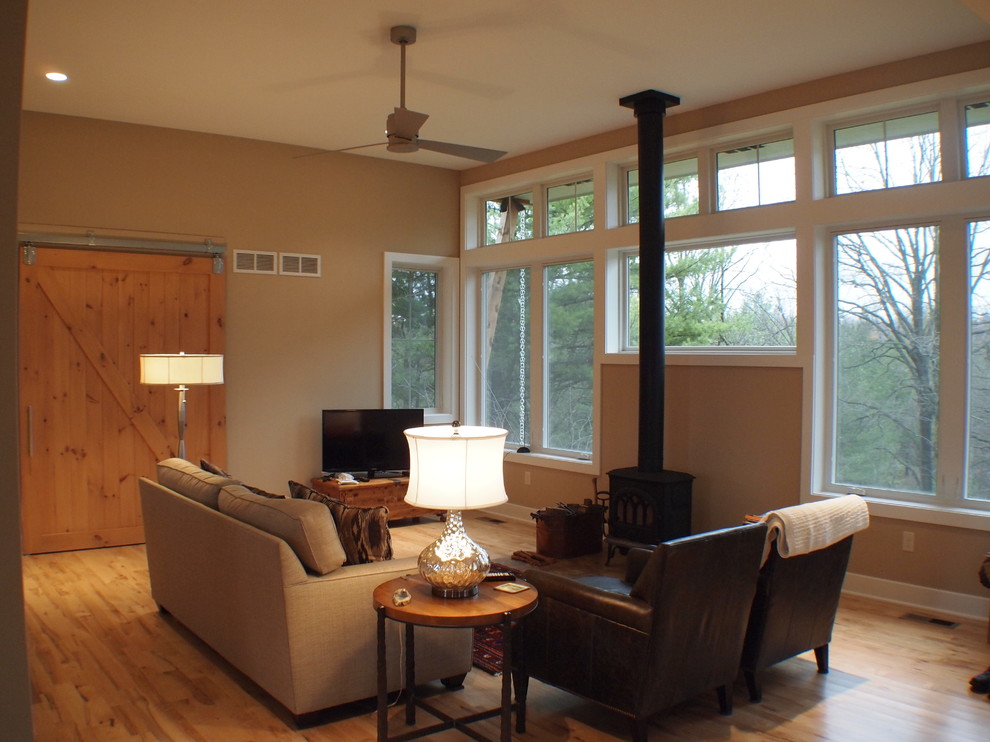 Idee per un piccolo soggiorno design aperto con pareti beige, parquet chiaro, stufa a legna e TV autoportante