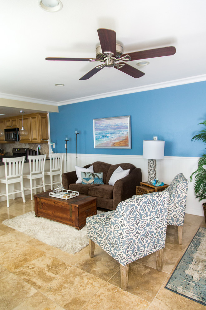 Modelo de salón abierto costero de tamaño medio sin chimenea con paredes azules, suelo de baldosas de cerámica y suelo beige