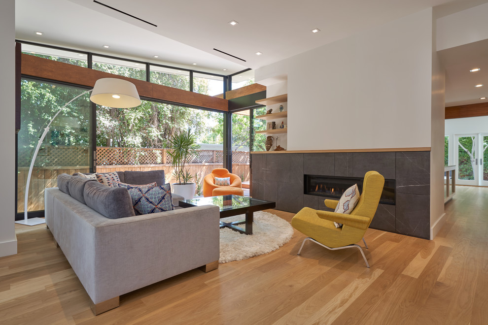 Medium sized midcentury enclosed living room in Los Angeles with white walls, medium hardwood flooring, a ribbon fireplace, a stone fireplace surround, no tv and yellow floors.