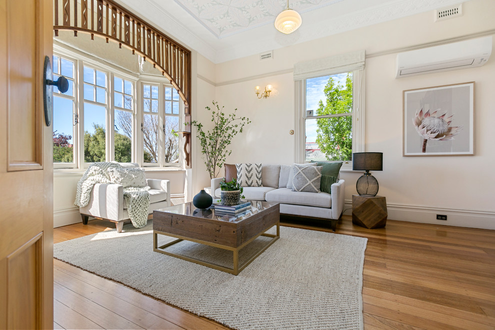 Transitional medium tone wood floor and brown floor living room photo in Hobart with beige walls