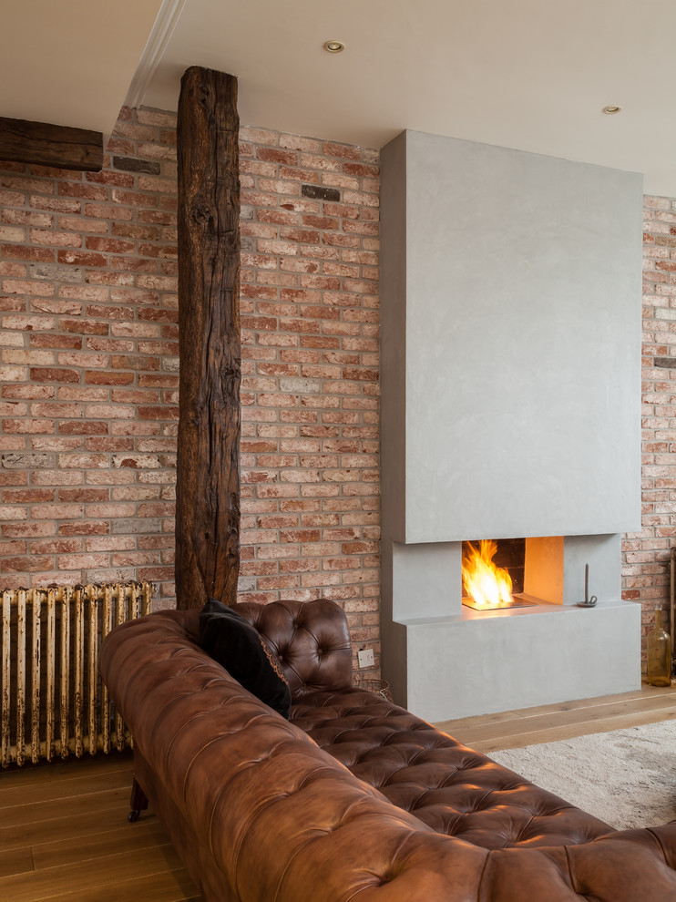 Example of an urban light wood floor living room design in London with a concrete fireplace
