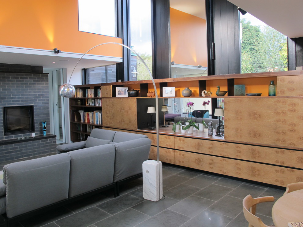 Small minimalist enclosed dark wood floor living room library photo in London with orange walls, no fireplace and a media wall