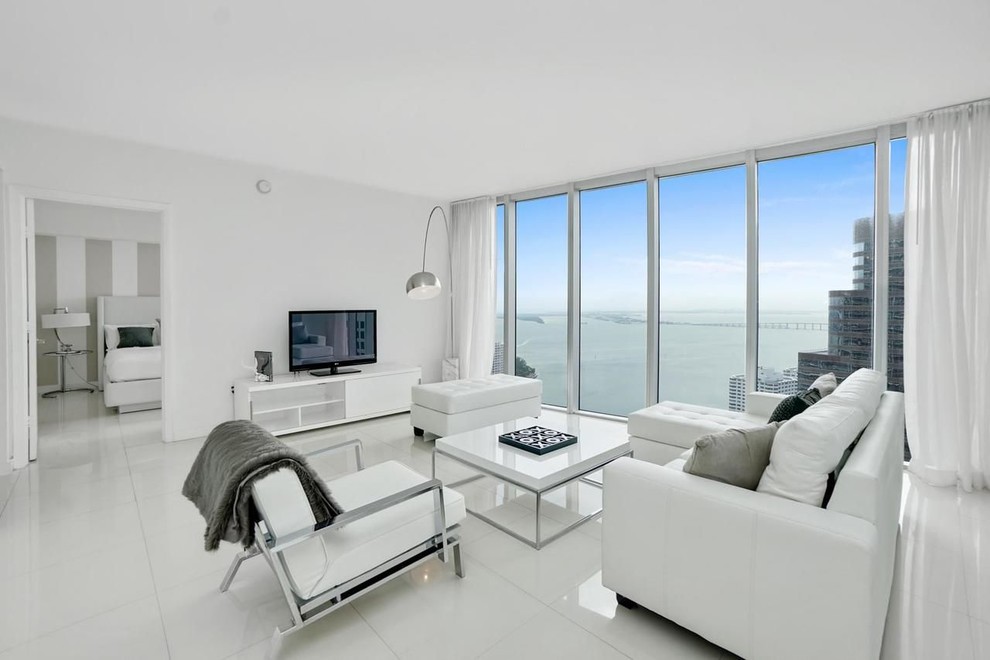 Imagen de salón abierto actual de tamaño medio con paredes blancas, suelo de baldosas de porcelana, televisor independiente y suelo blanco