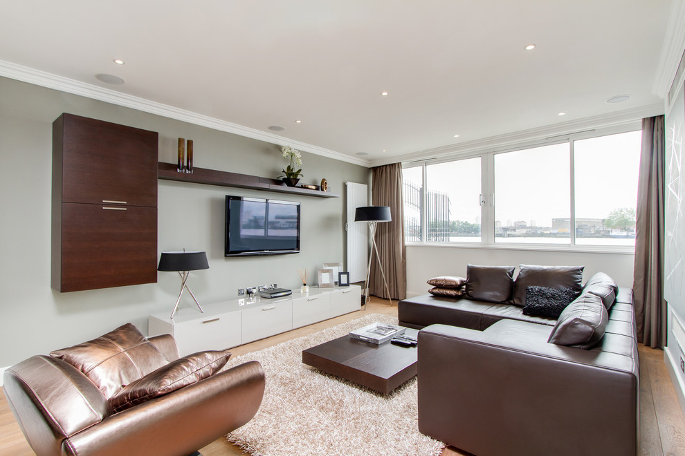 На фото: гостиная комната в современном стиле с серыми стенами и телевизором на стене