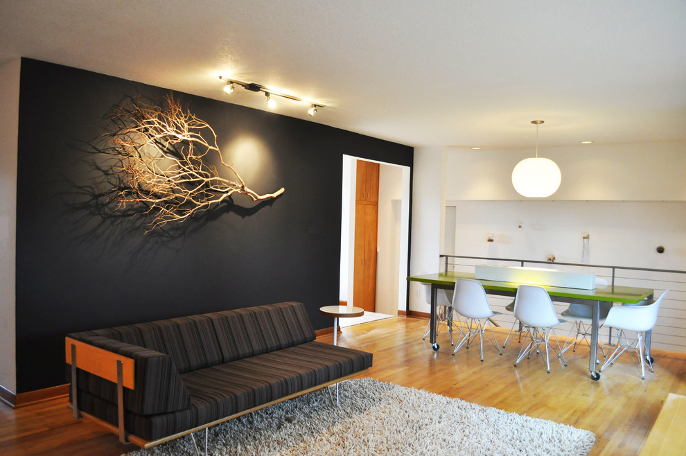 Example of a mid-century modern loft-style medium tone wood floor living room design in Portland with black walls